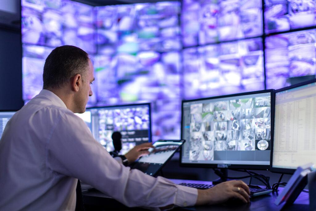 Control room e sala di sorveglianza con operatore davanti a videowall e monitor per il controllo delle telecamere.