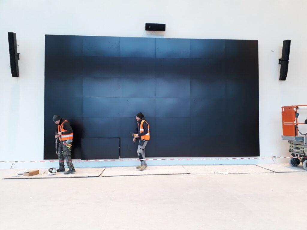 Tecnici al lavoro su grande display durante integrazione audio video e installazione audio video in ambiente professionale.