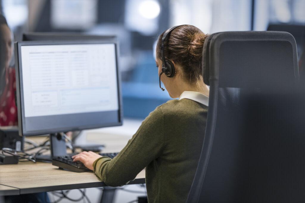 Operatrice con cuffie headset durante attività di assistenza audio video e supporto tecnico remoto.